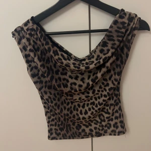Leopardmönstrad topp från Gina Tricot - Säljer en snygg leopardmönstrad topp från Gina Tricot. Toppen har en draperad halslinje och är ärmlös, perfekt för en trendig look. Passar utmärkt till både jeans och kjol. 🐆✨storlek S, använd en gång men passade ej då. 