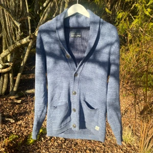 Blå kofta från Angelo Litrico - Säljer en snygg blå kofta från Angelo Litrico. Den har en stilren design med knappar framtill och två praktiska fickor. Perfekt för kyligare dagar och ger en avslappnad look.