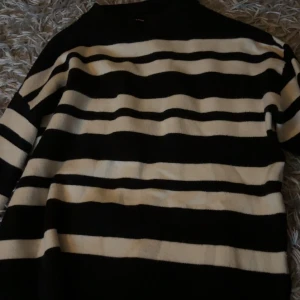 Randig svartvit tröja från Vero Moda - Snygg stickad tröja från Vero Moda i svart och vitt med breda horisontella ränder. Tröjan har lång ärm och en klassisk rund halsringning. Perfekt för dig som gillar en stilren och trendig look.