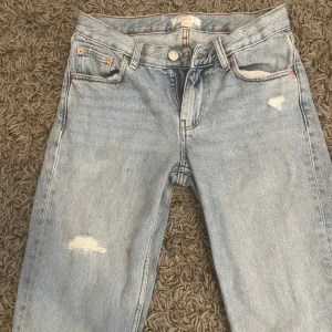 Ljusblå jeans från Gina Tricot, strl 152 - Säljer ett par ljusblå jeans från Gina Tricot i storlek 152. Jeansen har raka ben, klassisk femficksmodell och slitna detaljer framtill för en cool look. Perfekta till sneakers och hoodie. Materialet är klassisk denim i bomull.