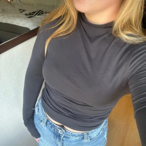 Grå långärmad Gina Tricot M - Säljer en grå tröja med lång ärm och tight passform. Tröjan har en hög hals och är tillverkad i mjuk bomull/polyesterblandning. Snygg detalj med slits i ärmsluten som ger en chill vibe. Perfekt att matcha med jeans eller kjol. Från Gina Tricot 