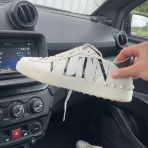 Valentino skor  - Snygga vita Valentino Garavani VLTN sneakers i skinn med svart VLTN-logga på sidan och coola nitar på hälen. Klassisk rund tå, snörning och platt sula. Perfekta för dig som vill sticka ut med en lyxig och trendig look. Skick 9/10 