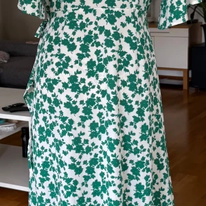 Grönvit blommig omlottklänning S - Säljer en superfin omlottklänning från Pernilla Wahlgren i storlek S. Klänningen är vit med grönt blommigt mönster, har korta ärmar och knyt i midjan. Lätt och flowy passform, perfekt för varma dagar. Materialet känns mjukt och luftigt mot huden.
