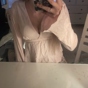 Ljusrosa tröja Gina Tricot XS - Supersöt ljusrosa tröja från Gina Tricot i storlek XS. Tröjan har omlott-design med v-ringning, långa ärmar och ett knytband i ryggen. Materialet är mjukt och lätt, perfekt för vår och sommar. Passformen är normal och ger en feminin siluett. ”Har använt max 1 gång” 