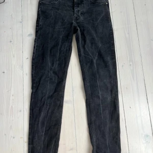 Svarta jeans från The Blue Uniform - Snygga svarta jeans från The Blue Uniform med klassisk femficksdesign och diskret logga på bakfickan. Jeansen har en smal passform och är tillverkade i mjukt denimtyg. Perfekta för dig som gillar en stilren och enkel look.