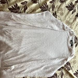 Ljusvit stickad tröja Signature L - Säljer en ljusvit stickad tröja från Signature i storlek L. Tröjan har ett subtilt vågigt mönster över hela ytan och ribbade muddar med snygga silverfärgade knappar vid ärmsluten. Perfekt för dig som gillar stilrena detaljer och mjuka material. A white long shirt, it’s very elegant and it’s a L. 