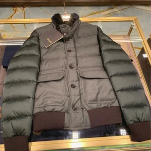 Mörkgrå pufferjacka från MooRER - Snygg mörkgrå pufferjacka från MooRER med quiltade ärmar och stora fickor framtill. Jackan har både dragkedja och knappar, samt ribbade muddar och krage i mjukt material. Perfekt för kalla dagar när du vill hålla stilen.