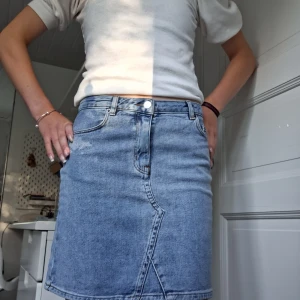 Blå jeanskjol från Carin Wester - Snygg ljusblå jeanskjol från Carin Wester i klassisk femficksmodell storlek 36. Ändast använd ett fåtal gånger, nypris rund 599kr. Kjolen har en rak, kort passform med coola sömdetaljer framtill och bakfickor. Perfekt att matcha med en enkel t-shirt eller hoodie för en chill look. 