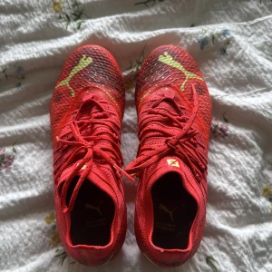 Röda Puma fotbollsskor med snörning - Snygga röda fotbollsskor från Puma med gula detaljer som är nästan helt oanvänd. Dom är i stolek 37. Pris kan diskuteras