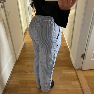 Byxor med knappar - Blå-vitrandiga byxor ifrån okänt märke 💌 Står strl L, för referens brukar jag ha strl M/38 i byxor och jag är 160 cm lång