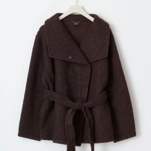 Brun jacka med bälte - Mysig brun jacka från Gina Tricot med omlottknäppning och brett slag. Jackan har ett matchande bälte i midjan och är tillverkad i ett ulligt material som ger en trendig look. Perfekt för kyliga dagar och enkel att styla till olika outfits.