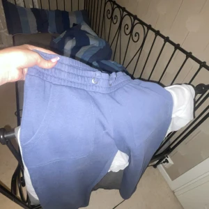 Blå mjukisbyxor med snörning - Säljer ett par blå mjukisbyxor med resår och snörning i midjan. Byxorna har stora fickor fram och bak, och är gjorda i mjukt bomullsmaterial. Perfekta för chill dagar eller när du vill vara extra bekväm.