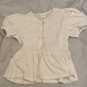 Krämvit blus med knyt från Gina Tricot - Supersöt krämvit blus från Gina Tricot. Använd 1 gång.