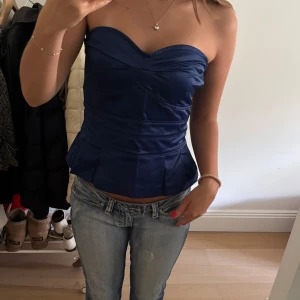 Marinblå axelbandslös korsettopp - Snygg marinblå korsettopp med axelbandslös bandeau-modell och markerad midja. 