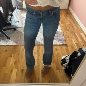 Bootcut jeans - Snygga blå lågmidjade jeans med bootcut passform och coola fickor med lock och knapp bak. Jeansen har normal midja och klassisk femficksdesign. Perfekta för dig som gillar en avslappnad men ändå trendig look.