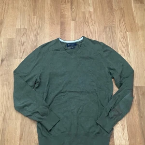 Olivgrön v-ringad tröja Riley XS - Olivgrön v-ringad tröja från Riley i storlek XS. Tillverkad i mjuk pima bomull som känns skön mot huden. Tröjan har långa ärmar och en klassisk, stilren look som funkar till jeans eller chinos. Perfekt för dig som gillar enkel och snygg stil.