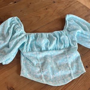 Ljusblå blus med puffärmar - Säljer en söt ljusblå blus med puffiga kortärmar och ett lätt rynkat tyg. 