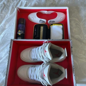 Air Jordan 4 oreo - Säljer ett par vita Nike Air Jordans med grå detaljer och snörning. Skorna kommer med en rengöringssats inklusive spray, borste och duk. Perfekt för att hålla dina sneakers fräscha! Har kvitto på dem från merchsweden!!