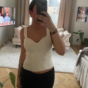 Vit ribbad linnetopp - Säljer en stilren vit ribbad linnetopp med breda axelband och en croppad passform. Perfekt för sommardagar eller som ett lager under en kavaj. Passar till både jeans och kjol.