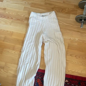 Vita randiga byxor - Säljer ett par vita byxor med diskreta ränder. Byxorna har en hög midja och en loose passform, vilket ger en bekväm och avslappnad stil. Perfekta för en stilren look.