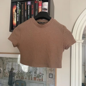 Beige ribbad croppad topp från Shein - Säljer en beige ribbad croppad topp från Shein. Den har en rund halsringning och korta ärmar, perfekt för en avslappnad stil. Toppen är i en mjuk och bekväm kvalitet.