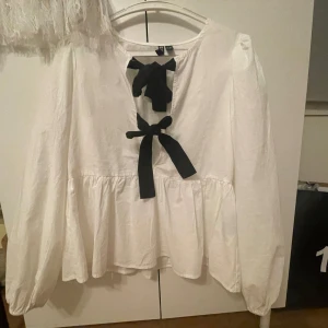 Blus med roset -  Vit blus med svarta rosetter storlek XS har aldrig använt skriva fler bilder om jag har några frågor 