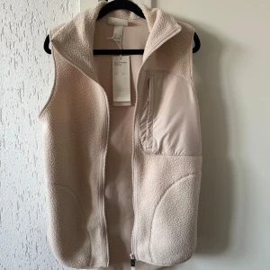 Beige fleeceväst  - Säljer en mysig beige fleeceväst från H&M. Passar perfekt som lager på lager eller utomhus nu när det börjar bli lite varmare. Helt ny med prislappen på. Oversize fit även som XS. 