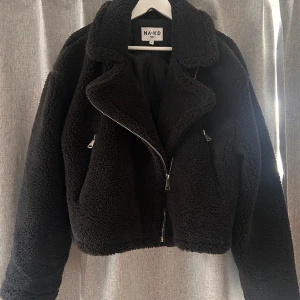 Svart teddyjacka från NA-KD - Säljer en snygg svart teddyjacka från NA-KD. Jackan har en dragkedja framtill och vid ärmsluten. Köpt för något år sedan men endast använd ett par gånger och är i nyskick men säljer då den inte är min stil. Perfekt som vårjacka 🖤skriv för flera bilder eller frågor!