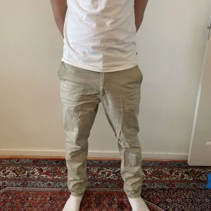 Beige chinos - Snygga beige chinos med normal passform och midwaist. Perfekta för en avslappnad stil. De har en klassisk design med dragkedja och knappar. nypris 999kr