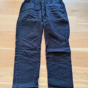 Svarta byxor från Woodbird - Säljer ett par svarta byxor från Woodbird i storlek M. Byxorna har en elastisk midja och är tillverkade i ett mjukt material. Perfekta för en avslappnad stil. Nypris 1000kr och mitt pris 200kr!!!