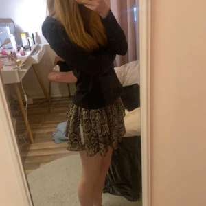 Ormmönstrad kjol med volanger - Snygg kortkjol med ormmönster och volanger. Köpt på Lindex för några år sedan på barnavdelningen den är i storlek 146/152 men passar som XS, inga defekter 💕