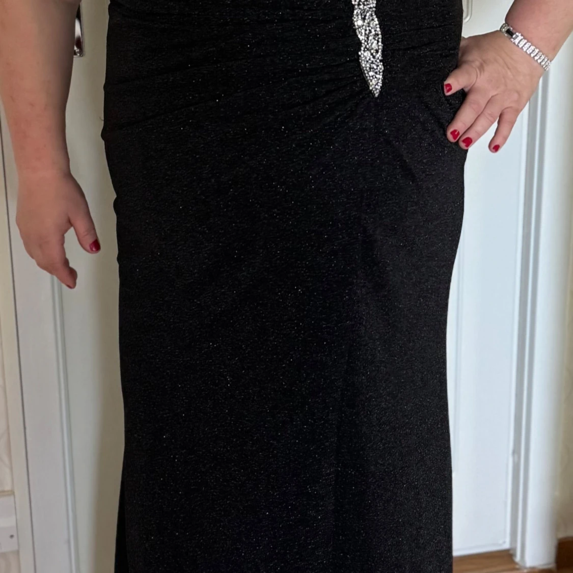 Svart glittrig långklänning med dekorativ detalj