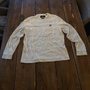 Vit långärmad tröja från Lyle & Scott - Säljer en stilren vit långärmad tröja från Lyle & Scott med deras ikoniska logga på bröstet. Perfekt för en avslappnad look. Tröjan har en rund halsringning och är tillverkad i ett mjukt material. Tveka inte att höra av dig vid frågor!! Storlek S men skulle säga att den passar M också! 