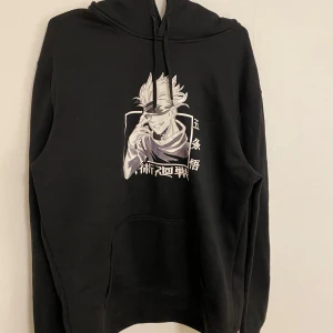 Jujutsu kaisen hoodie anime - Anime hoodie med japansk text på ärmarna ”呪術廻戦” (jujutsu kaisen) samt tryck på Satoru Gojo på tröjans framsida. Normalstor huva och magficka! Trycket på framsidan kan ses som minimalt skrynklig men har ingen påverkan på helhetsintrycket. Mycket bra skick!