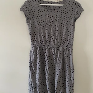 Grå prickig klänning från H&M - Säljer en söt grå klänning med svarta prickar från H&M. Klänningen har korta ärmar och knappar i ryggen. Perfekt för en avslappnad stil. Storleken är 158 cm men passar ävem damstorlek S🖤