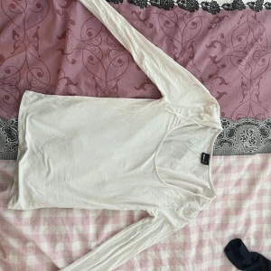 Vit långärmad topp från Gina Tricot - Säljer en vit långärmad topp från Gina Tricot. Perfekt för lager-på-lager eller att bära som den är. Toppen har en enkel design med rund halsringning.