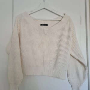 Vit stickad tröja från Gina Tricot - Säljer en stilren vit stickad tröja från Gina Tricot. Tröjan har en bred v-ringning och långa ärmar. 