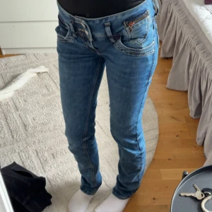 Blå jeansbyxor med låg midja - Snygga blå jeansbyxor från G-Star med låg midja och en tight passform. Byxorna har en klassisk femficksdesign och knappar framtill. Perfekta för en avslappnad stil.