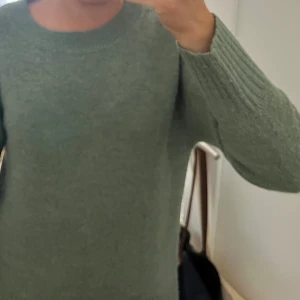 Grön stickad tröja - Säljer en mysig grön stickad tröja med rund hals och långa ärmar. Perfekt för kyligare dagar och enkel att matcha med olika outfits. Tröjan har ribbade muddar vid ärmslut och nederkant. Tröjan är i storlek XS men passar S💚