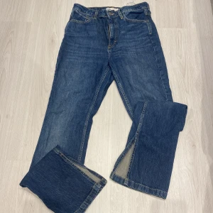 Blå jeans från Zara - Säljer ett par klassiska blå jeans från Zara. De har en rak passform och är tillverkade i denim med fem fickor och knappgylf. Perfekta för en avslappnad stil.