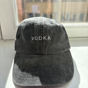 Grå keps med broderad text - Snygg grå keps med justerbart spänne och broderad text 'VODKA' framtill. Perfekt för en avslappnad stil.
