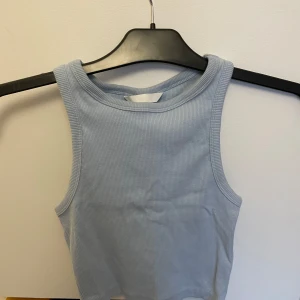 Ljusblå ribbad linnetopp från H&M - Säljer en ljusblå ribbad linnetopp från H&M. Toppen är ärmlös och har en rund halsringning, perfekt för varma dagar. Enkel och stilren design som passar till det mesta. Perfekt för sommaren! 💙