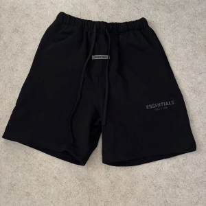 Svarta shorts från Essentials - Snygga svarta shorts från Essentials med logga på benet. De har en bekväm passform med snörning i midjan. Perfekta för en avslappnad stil.
