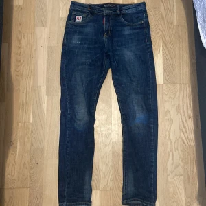Mörkblå jeans från AJ - Snygga mörkblå jeans från AJ med en klassisk femficksdesign. Jeansen har en diskret tvättad look och en patch med AJ-loggan på bakfickan. Perfekta för en avslappnad stil.