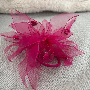 Rosa hårsnoddar med blommor - Snyggt rosa hårsnoddar med stora, fluffiga tyllblommor och små rosdetaljer. Perfekt för att ge en färgglad touch till din outfit.