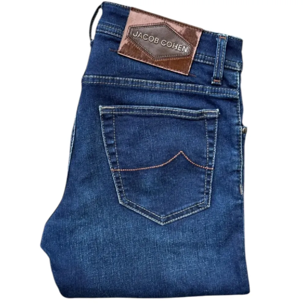 Snygga blå jeans från Jacob Cohen med klassisk femficksdesign och knappgylf. Tillverkade i Italien med högkvalitativt material för en stilren look. Perfekta för en avslappnad men ändå elegant stil. Modell nick.. Farkut & Housut.