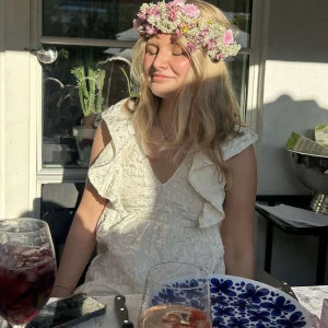 Vit klänning med volangdetaljer - Söt vit klänning med volangdetaljer och v-ringning. Har en fin öppen rygg som man knyter där bak!!!