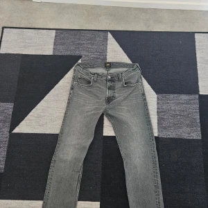 Grå jeansbyxor från Lee - Snygga grå jeansbyxor Lee med en klassisk femficksdesign. Byxorna har en rak passform och är tillverkade i ett slitstarkt denimtyg. Perfekta för en stilren vardagslook.
