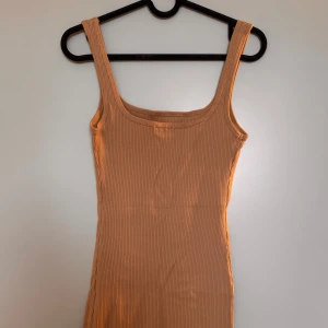 Ljusbrun ribbad mini-klänning - En ljusbrun/beige ribbad klänning. Skön och stretchig, perfekt för festliga tillfällen. Klänningen har en snygg passform som framhäver siluetten. Använd endast en gång - ny skick!