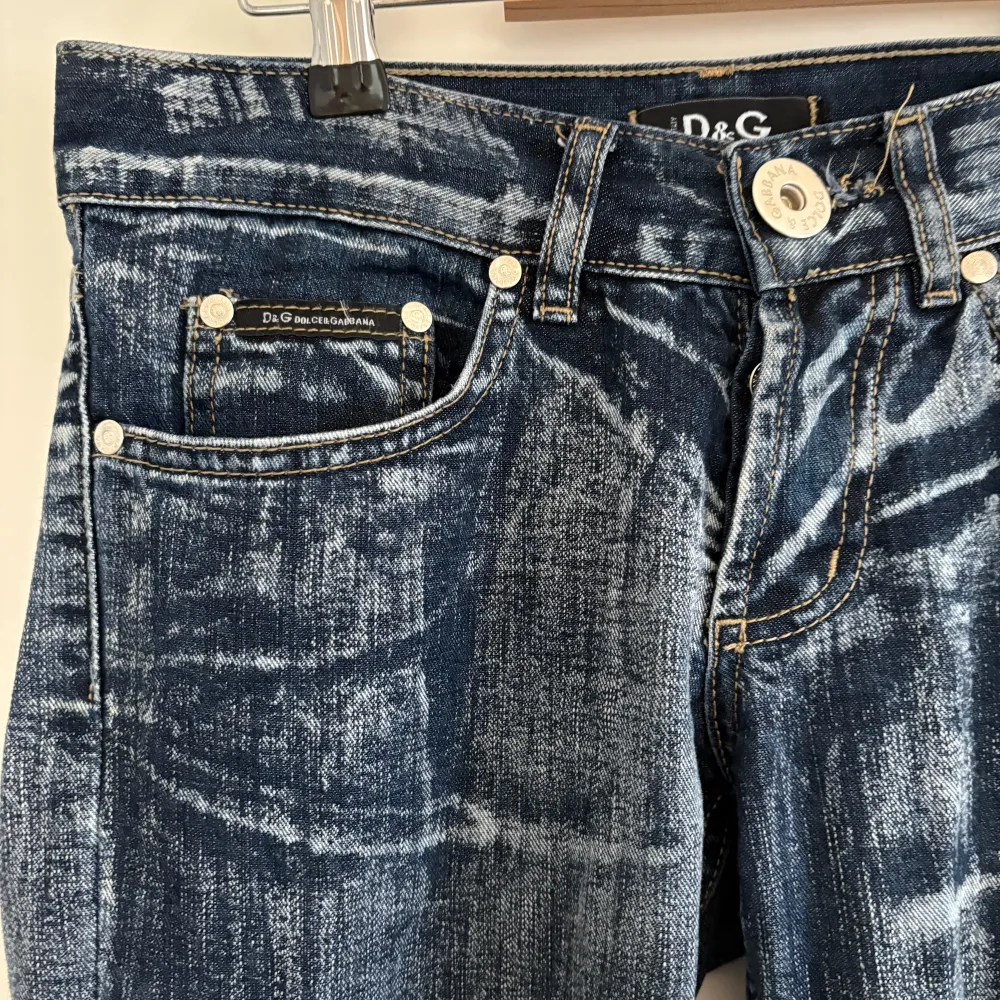Snygga blå jeans från dolce and Gabbana med unika broderade detaljer på bakfickorna. Jeansen har en klassisk femficksdesign och en cool tvättad look. Perfekta för dig som vill ha något extra i garderoben! Utsvängda lågmidjade. Mått: midja: 75 cm innerben: 78 cm. Farkut & Housut.